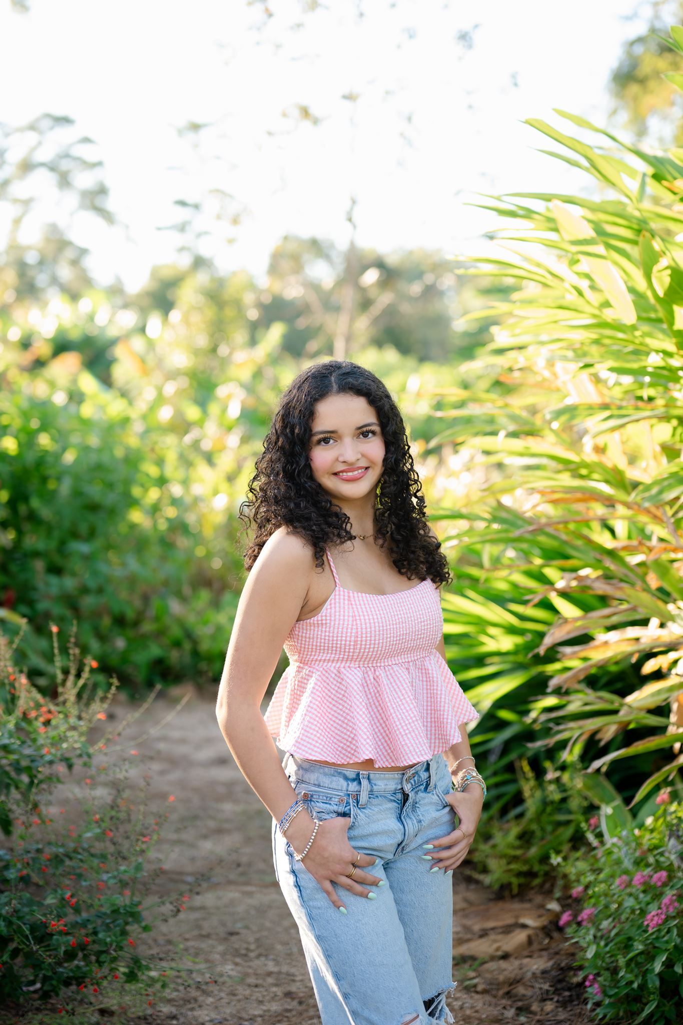 The Woodlands senior girl with curly hair posing among greenery at Mercer Botanic Gardens.