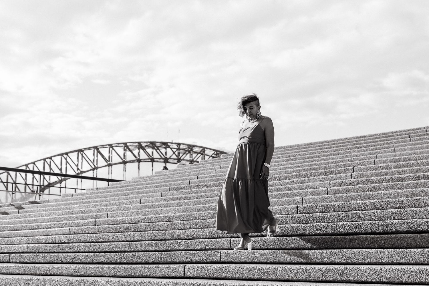 Woman with blue hair poses by Sydney Harbour Bridge waterfront in a sequined dress.