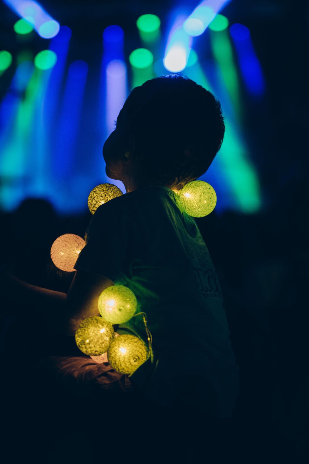 Silhouette holding glowing yellow orb lights against blue stage lighting.