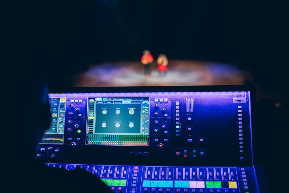 Digital audio mixing console with blue LED lights in dark environment.