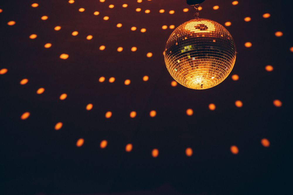Illuminated disco ball casting orange light patterns in dark space.