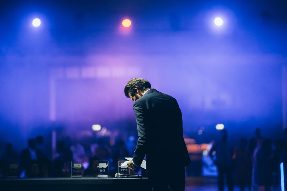 DJ performing at a concert with dramatic blue stage lighting.