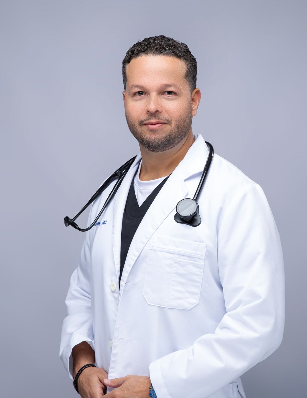 Doctor in a white coat on a light gray backdrop, LinkedIn headshot