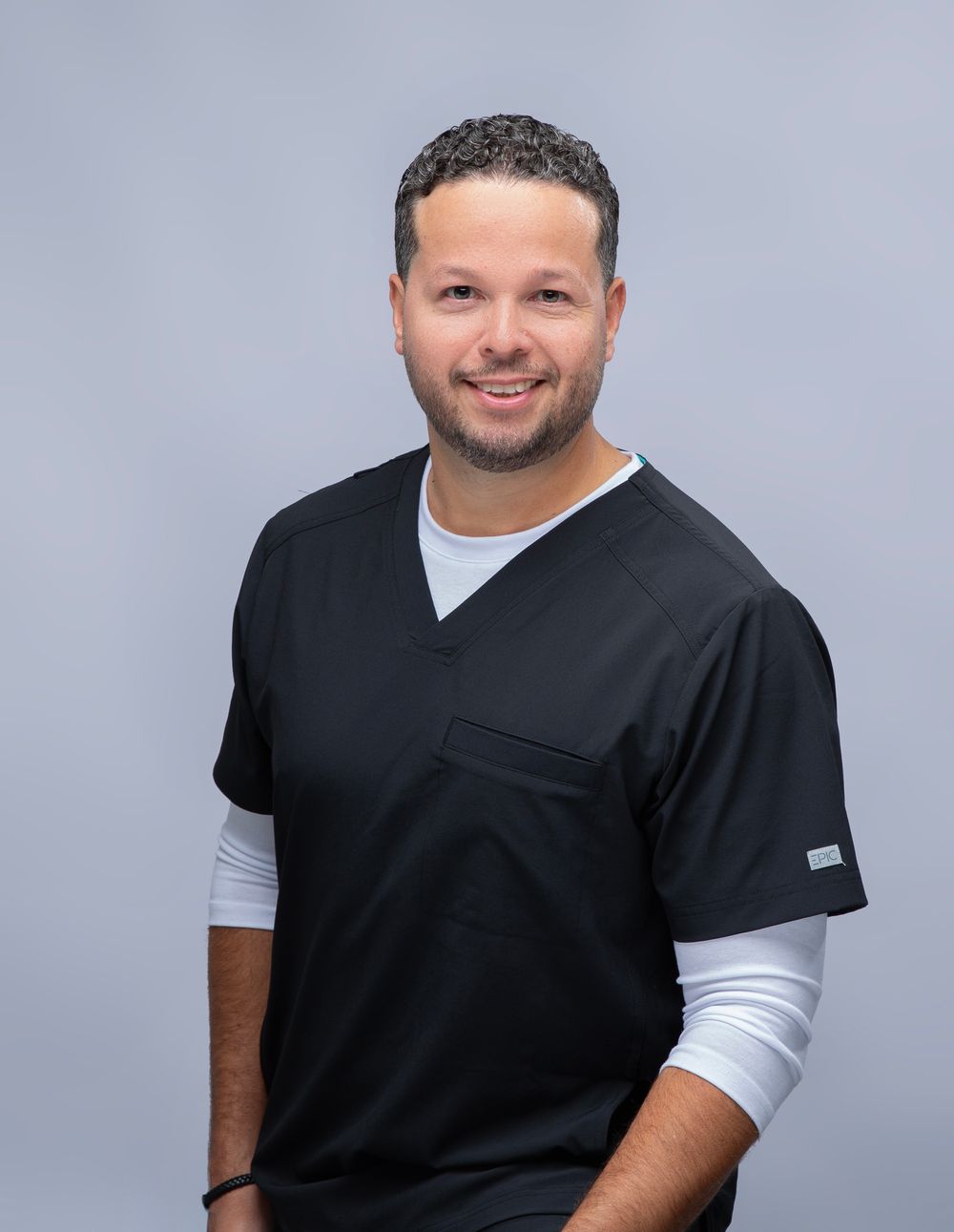 Man in black scrubs on a light gray backdrop, personal branding headshot