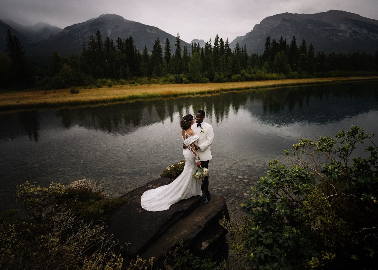 Bride and groom by a mountain pond at Silvertip Resort, Canmore wedding photographer