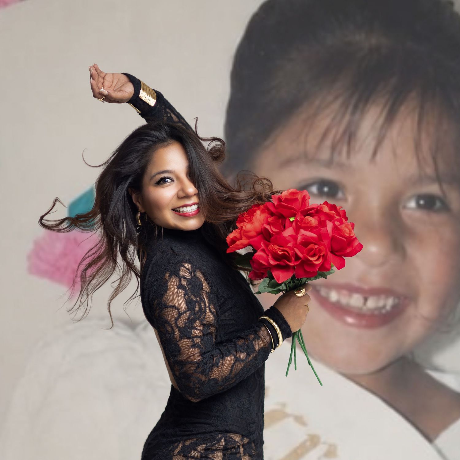 Woman in black lace dress holding red roses bouquet, posing in front of a large childhood photo backdrop.
