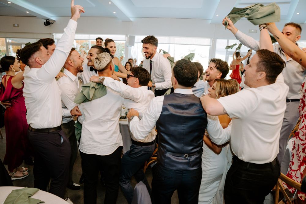 Energetic wedding guests celebrating together in a lively group dance at the reception.