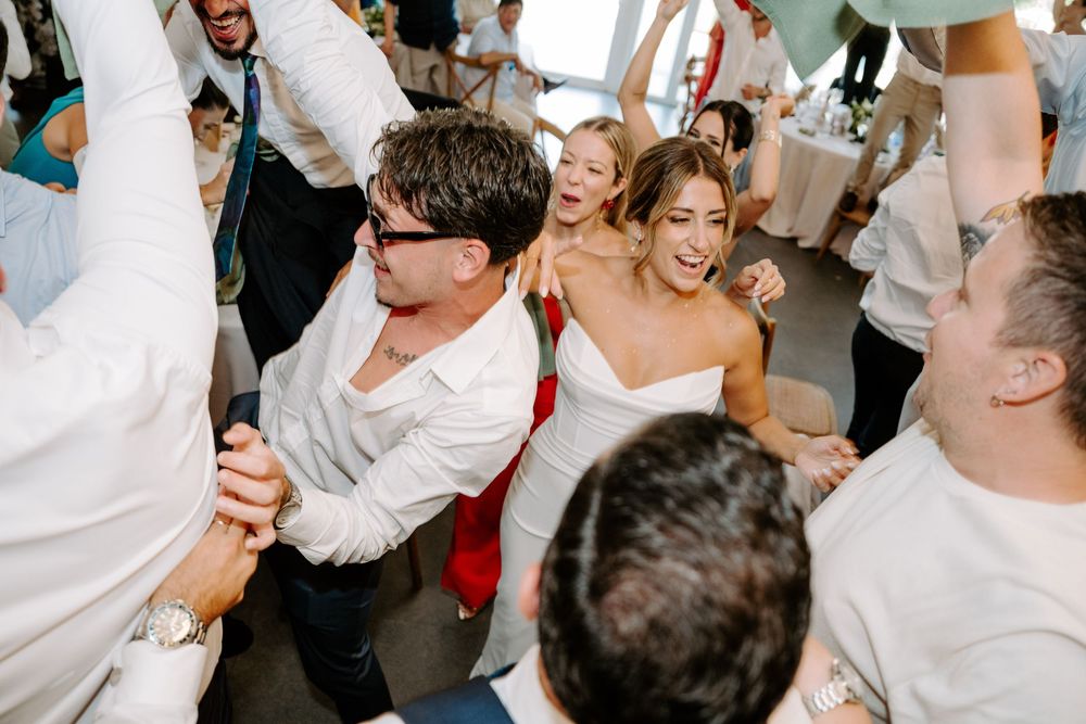 Bride and guests celebrating together in joyful wedding reception dance crowd.