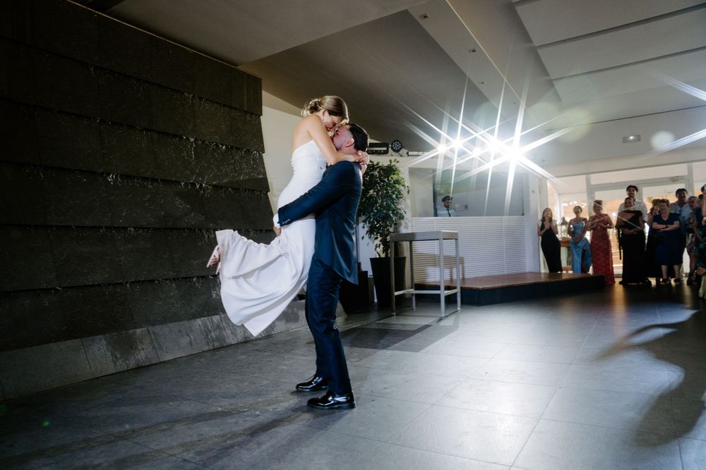 Groom lifting bride during romantic first dance at elegant wedding reception.