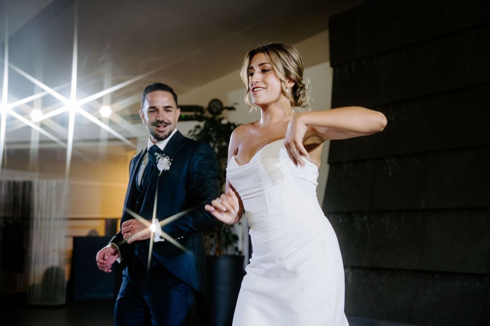 Bride and groom sharing a first dance together under sparkling lights at wedding.