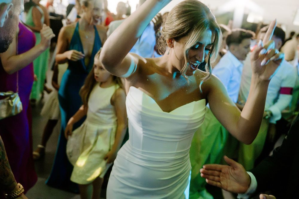 Bride in white gown dancing joyfully on the dance floor at wedding reception.