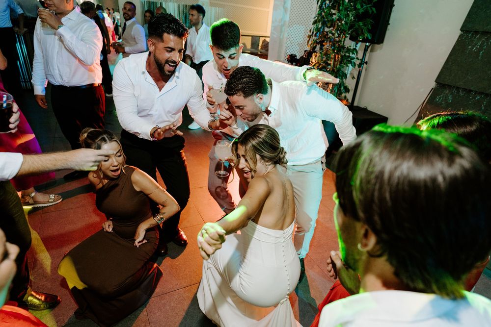 Bride and groom dancing closely with guests at vibrant colorful wedding reception celebration.