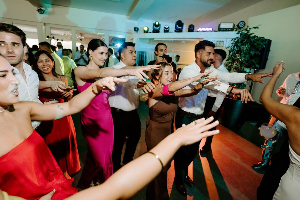 Guests dancing energetically at a lively wedding reception party on the dance floor.