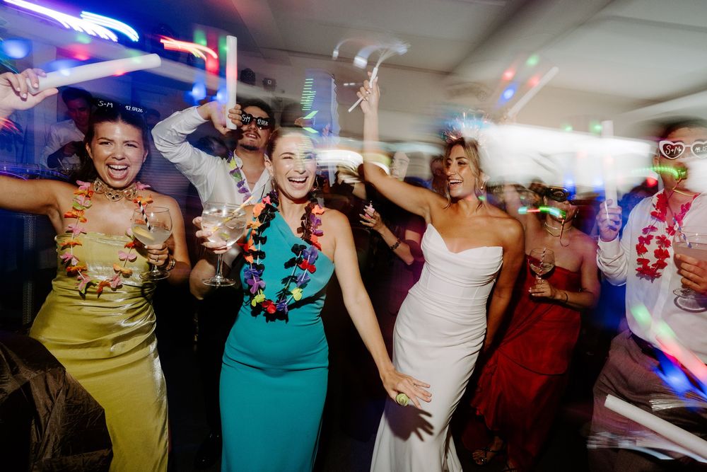 Bride and friends dancing with leis at a wedding reception.