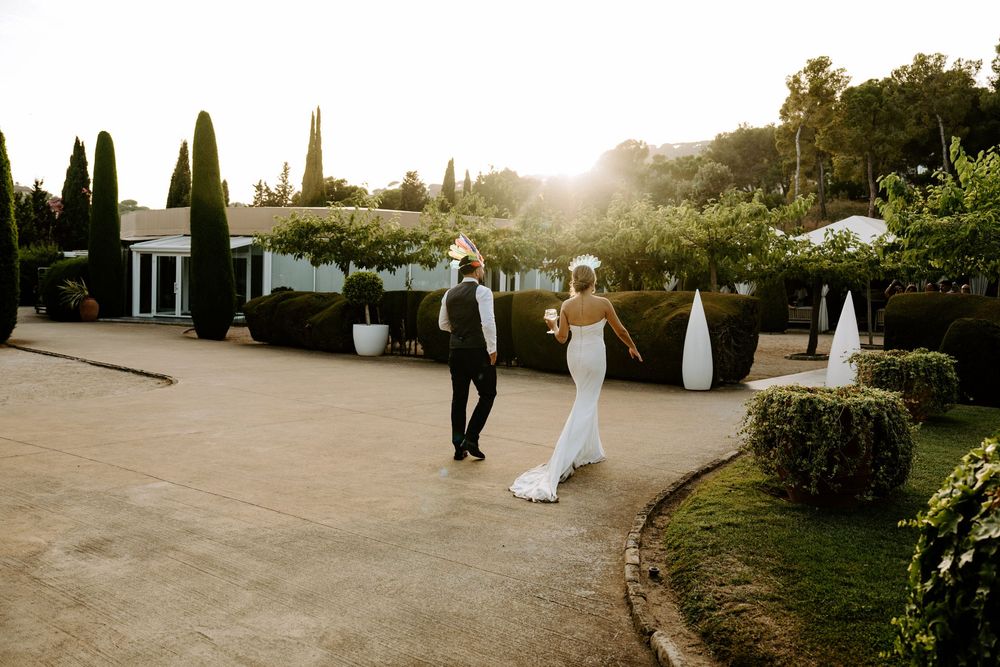 Bride and groom dancing at golden hour in an elegant garden venue with cypress trees.