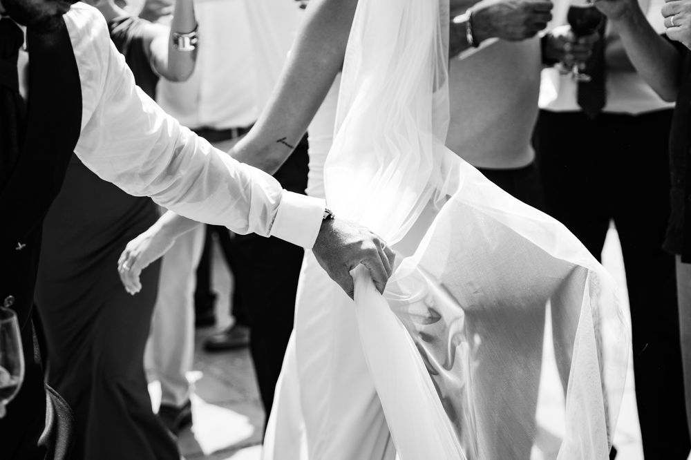 Black and white photo of bride and groom holding hands during their first wedding dance.