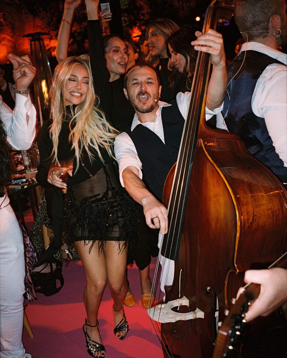 Guests dancing and celebrating at a lively party event with a double bass musician performing nearby.