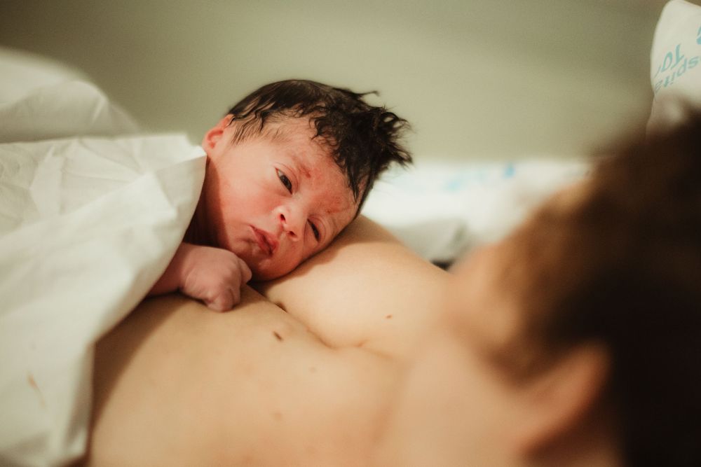 Newborn baby resting on mother's chest during skin-to-skin contact after birth in hospital.