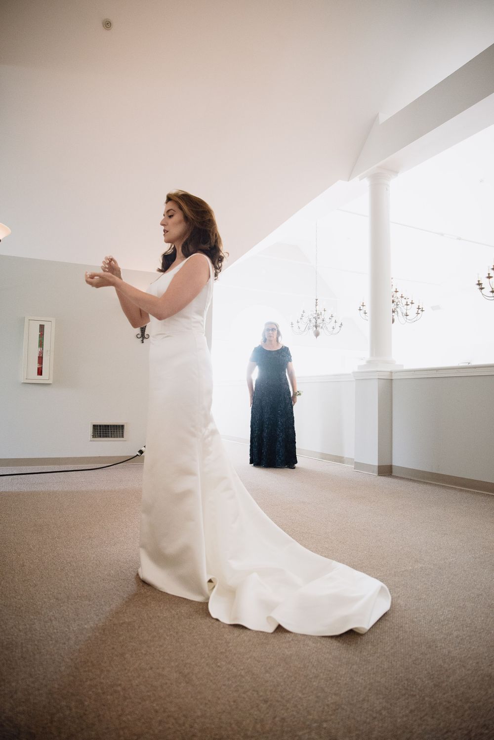 Flowing white wedding dress photographed in bright modern interior space.