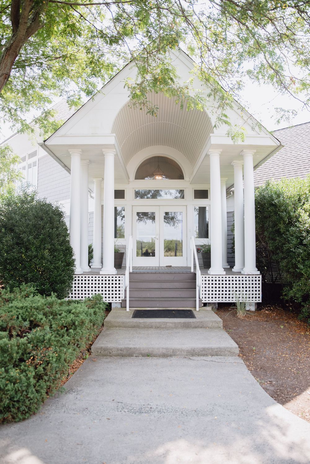 White wedding chapel entrance with grand columns and arched doorway surrounded by lush greenery.