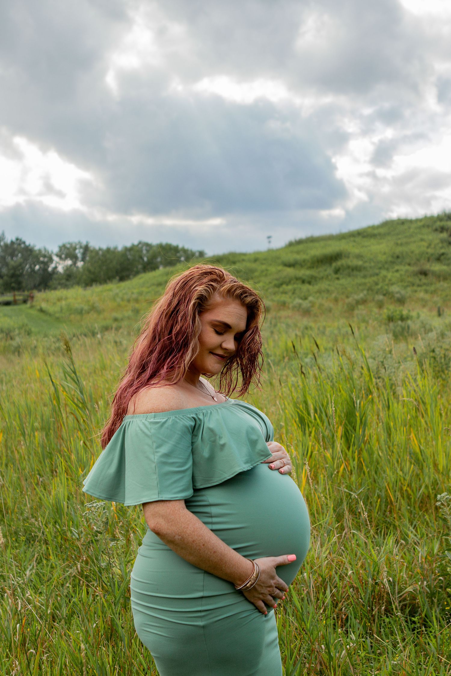 Pregnant mom holds her belly in a field in berea.