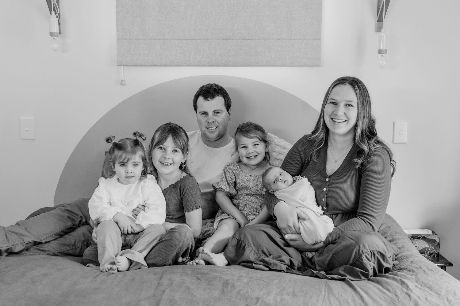 family sitting on bed with a newborn
