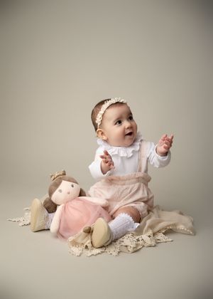 Baby sitting with a stuffed animal during a simple milestone photography session in New Jersey.