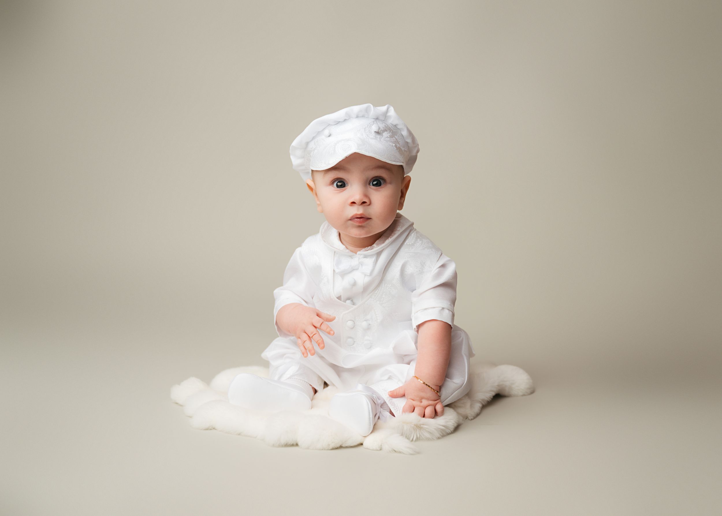 Baby boy in a white baptism outfit during a milestone photography session in New Jersey.