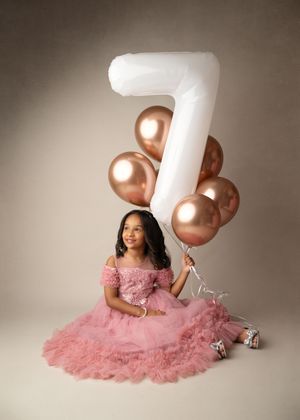Young girl celebrating a birthday with simple number balloons during a milestone portrait session.