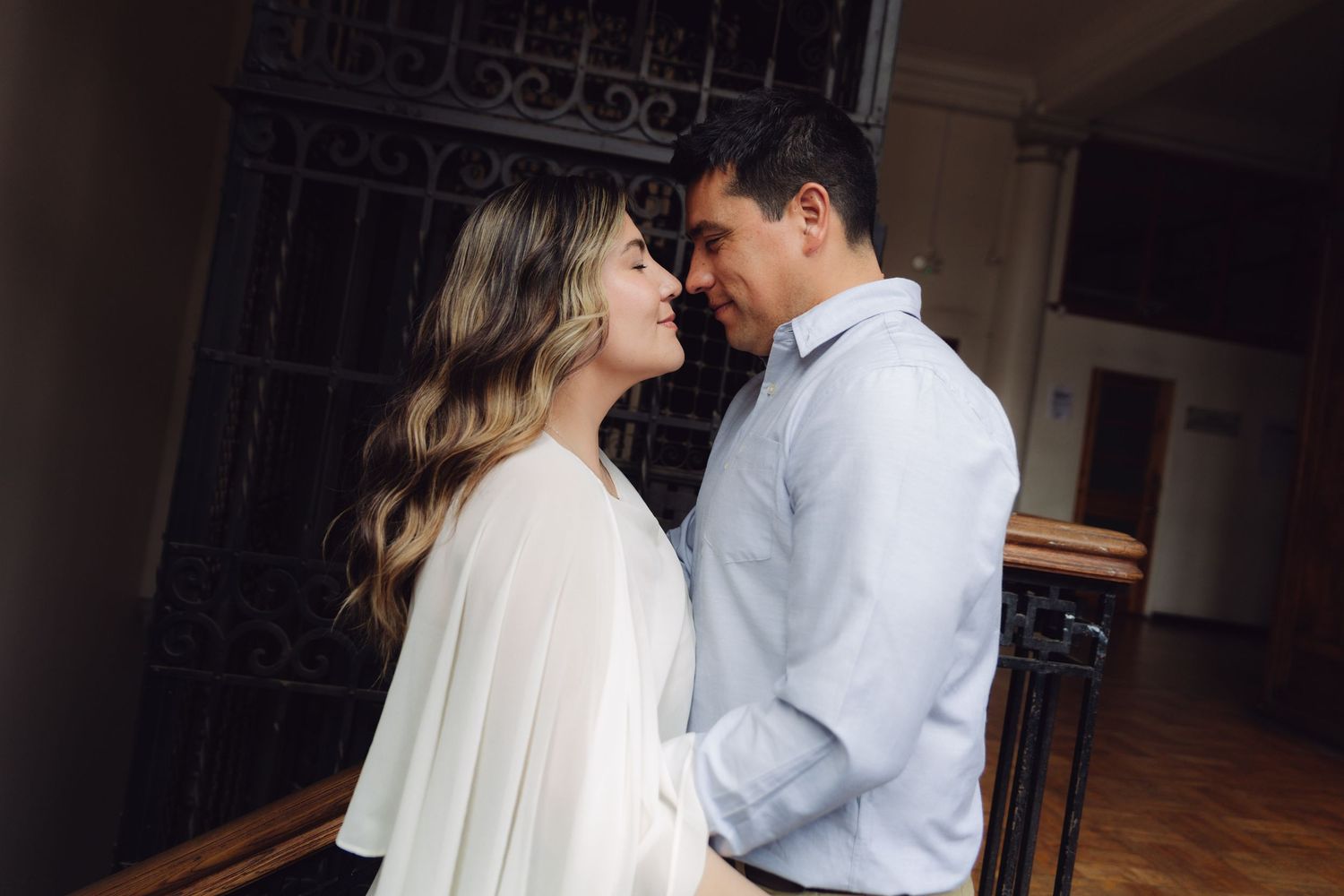 Romantic couple sharing an intimate moment, facing each other tenderly in an elegant indoor setting.