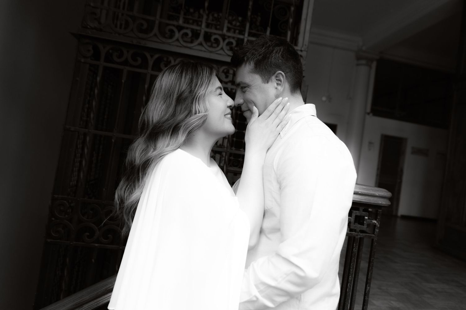 Black and white romantic photo of couple facing each other tenderly in soft light.