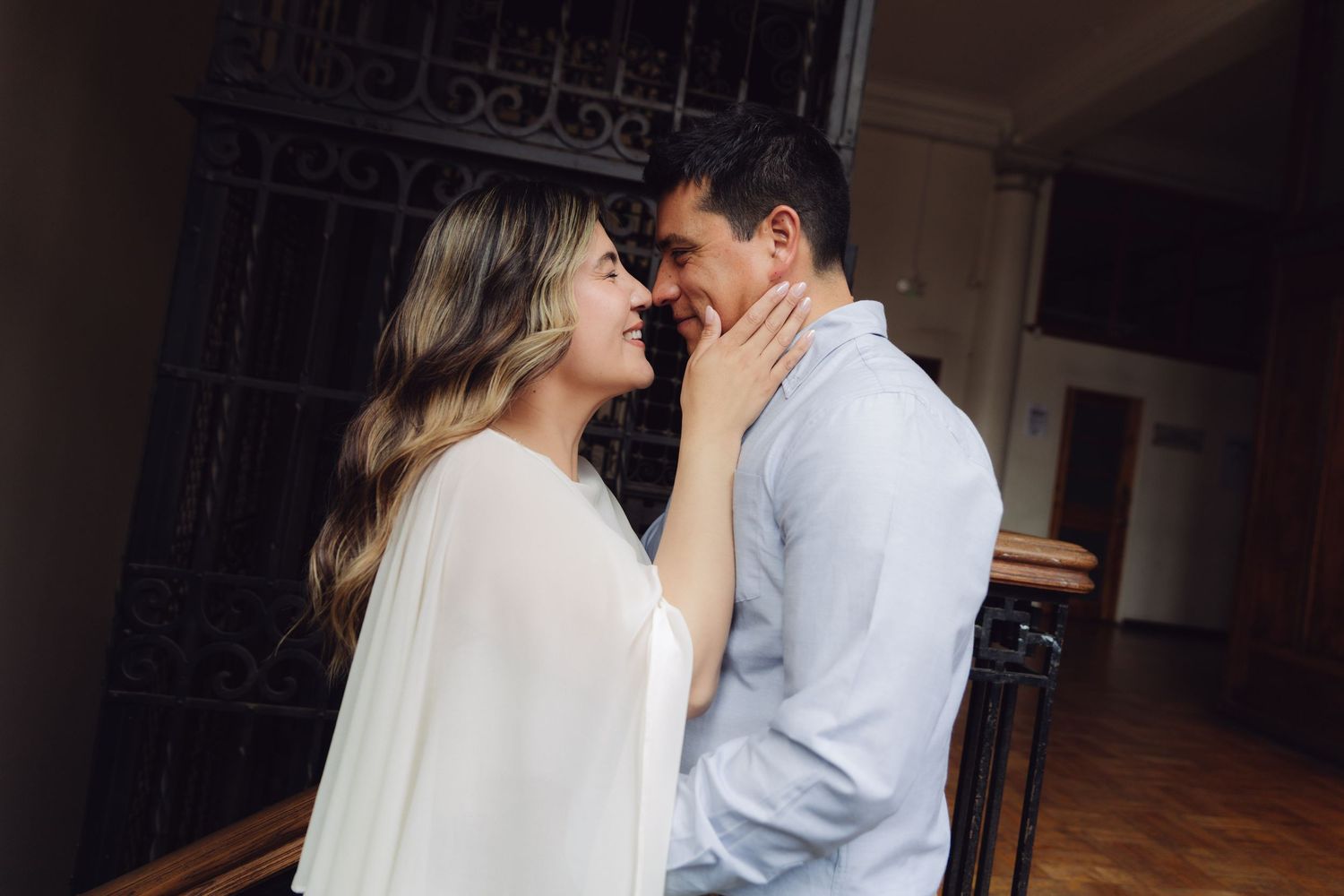 Loving couple almost kissing, woman gently touching mans face in a romantic indoor moment.