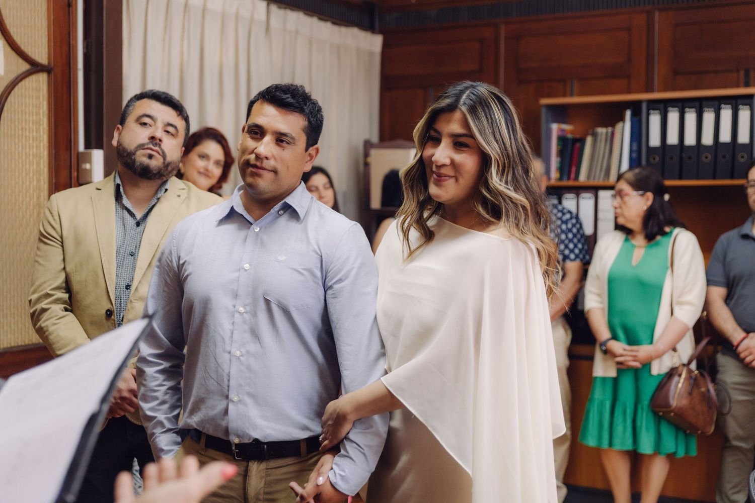 Couple walking together during civil wedding ceremony in a formal office with guests present.