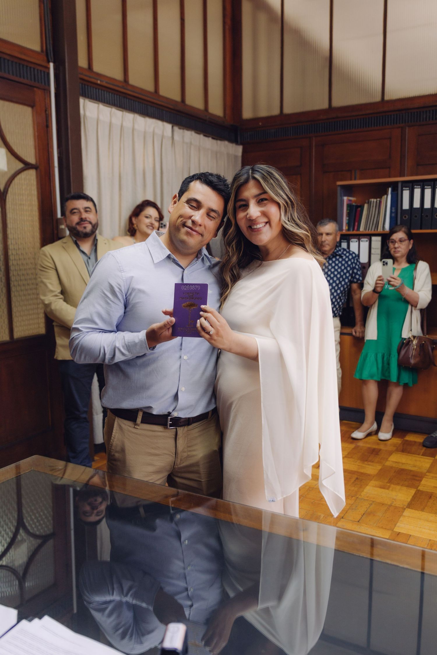 Newlywed couple proudly holding their marriage certificate booklet after civil wedding ceremony.