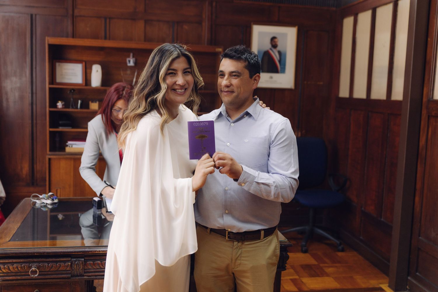 Happy newlywed couple displaying their official purple marriage certificate booklet after ceremony.