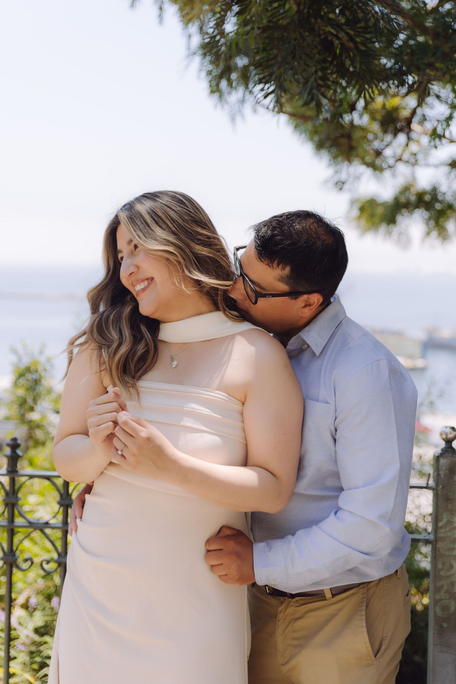 A joyful couple shares a tender moment at an outdoor terrace overlooking a beautiful coastline.