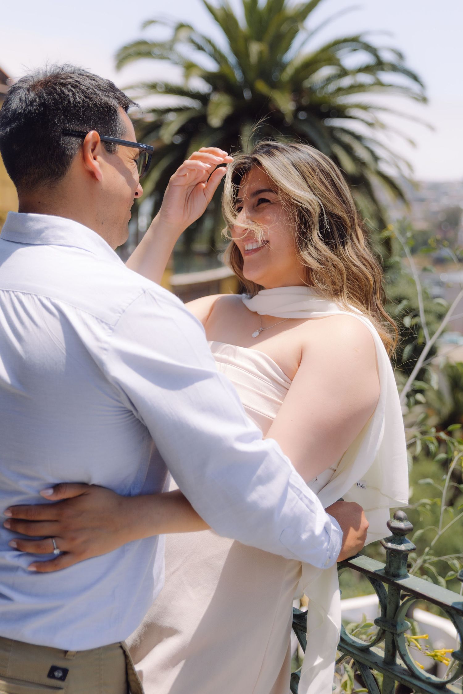 Man gently brushes hair from smiling woman's face during a romantic outdoor couples photo session.