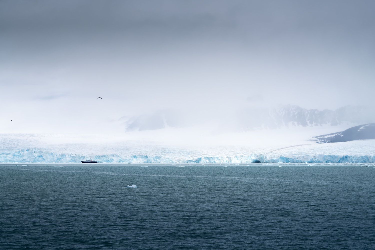 Navire minuscule devant un front glaciaire noyé de brume au Svalbard