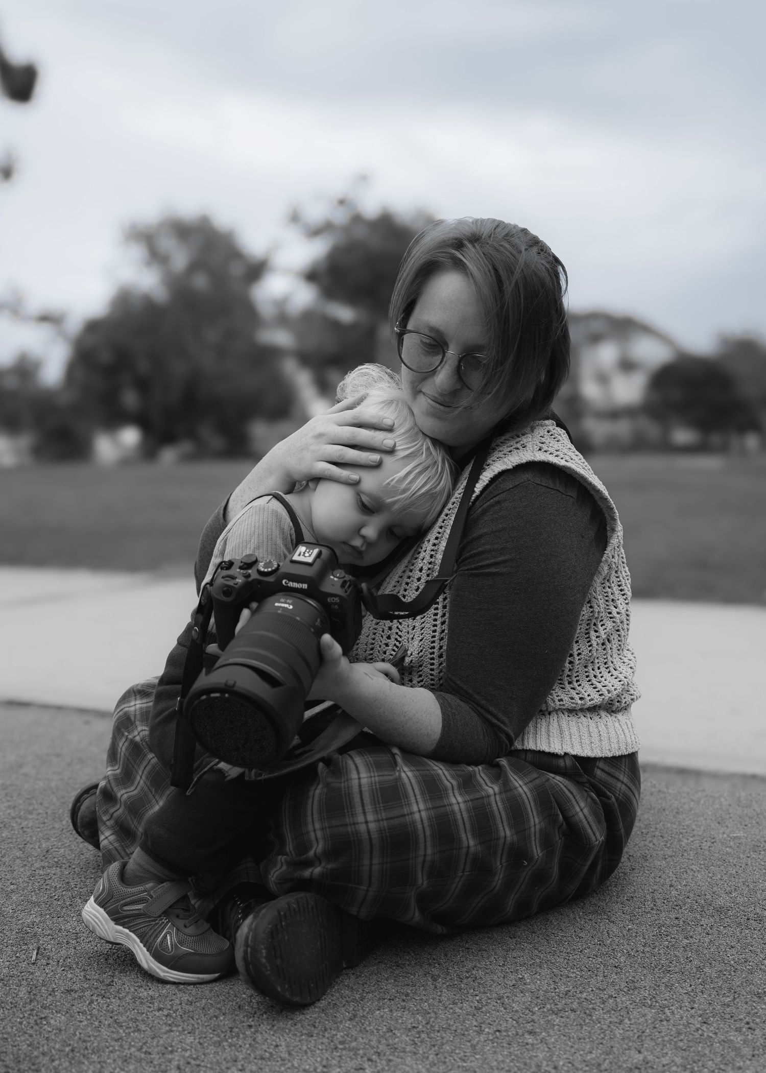 Woman carrying newborn baby in colorful rainbow dragon wrap sling carrier outdoors in natural setting.