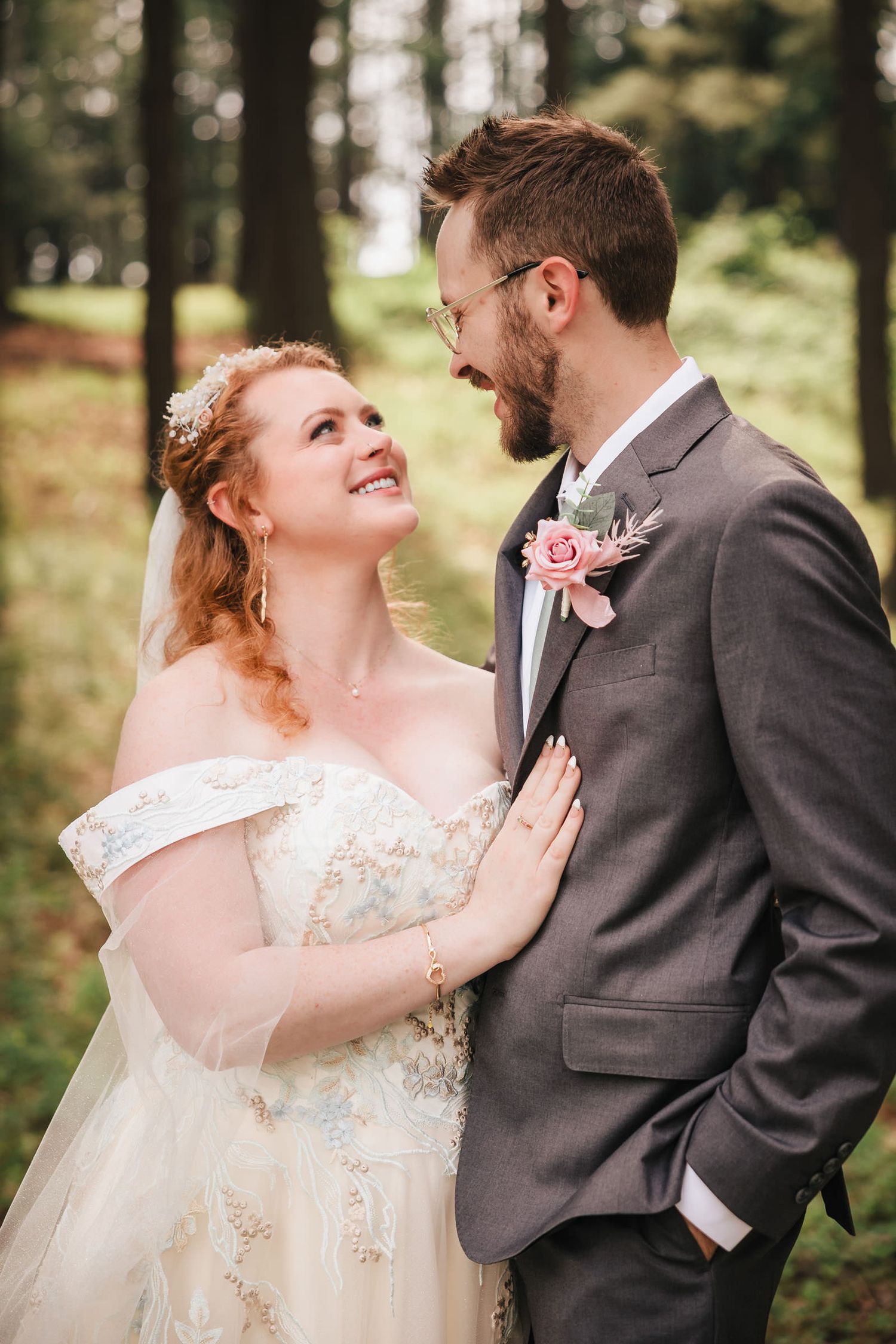 Close-up of the bride laughing as she looks up at the groom, his hand on her waist.