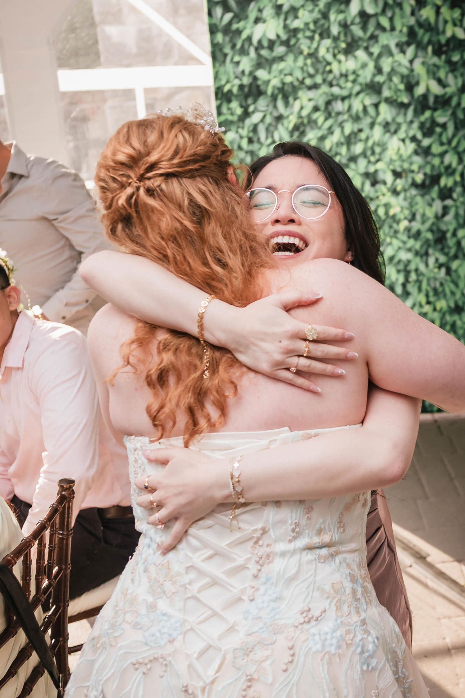 Bride embracing a laughing guest in a tight hug during the reception.