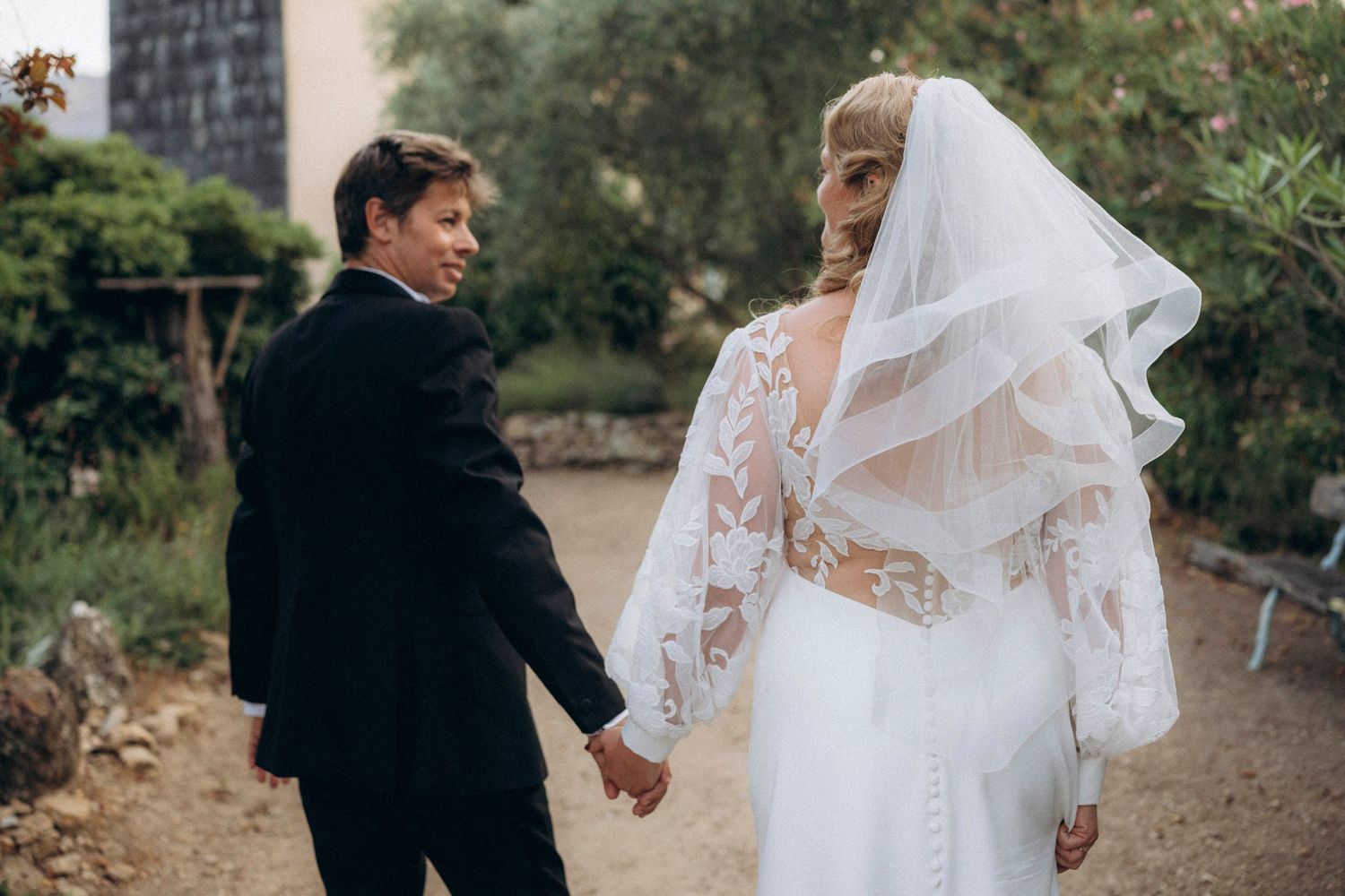A romantic black and white wedding photograph showing a tender embrace in a natural outdoor setting.