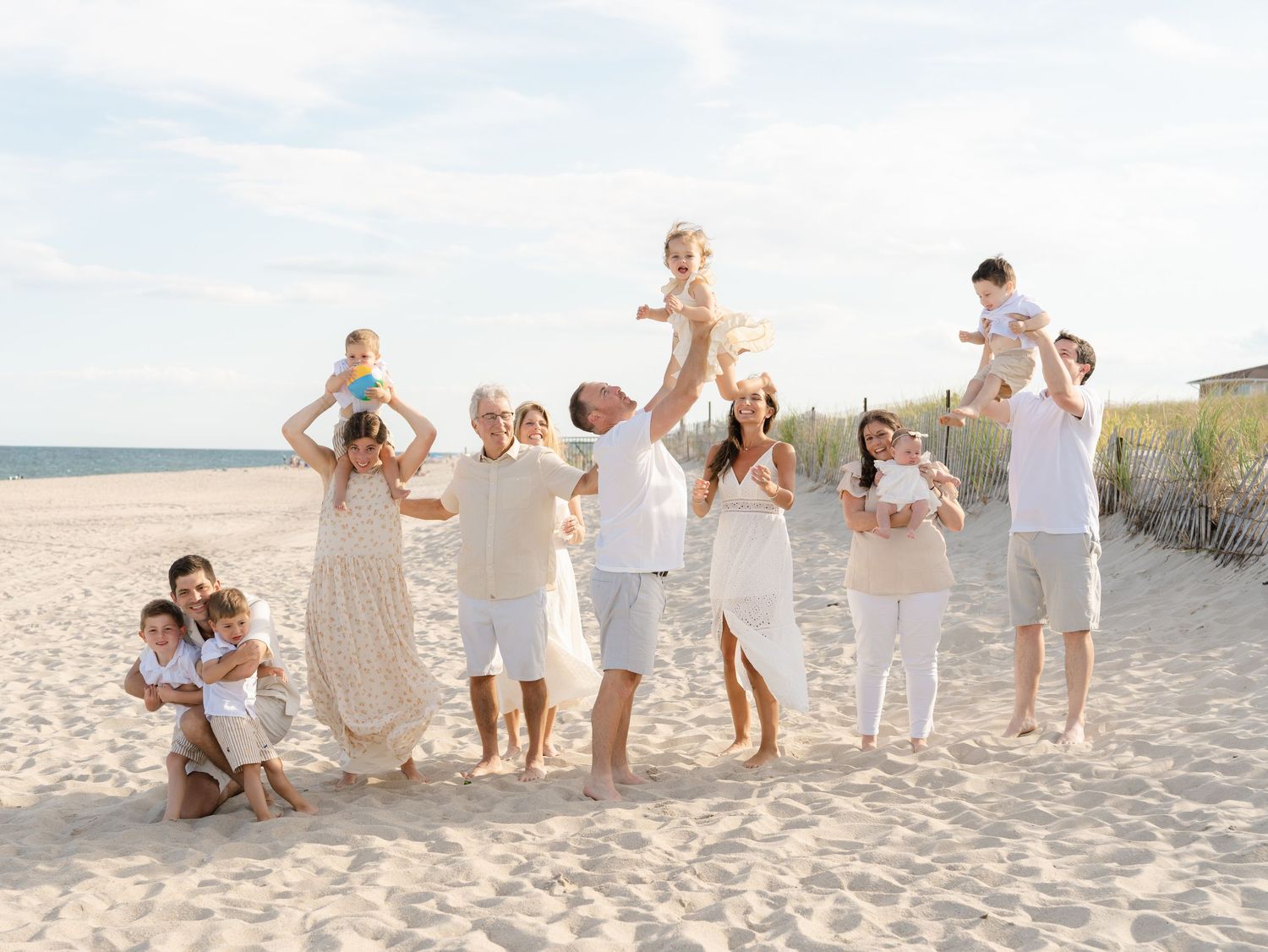 Adult siblings laughing together with their children on the shoreline during a ocean county family portrait session.