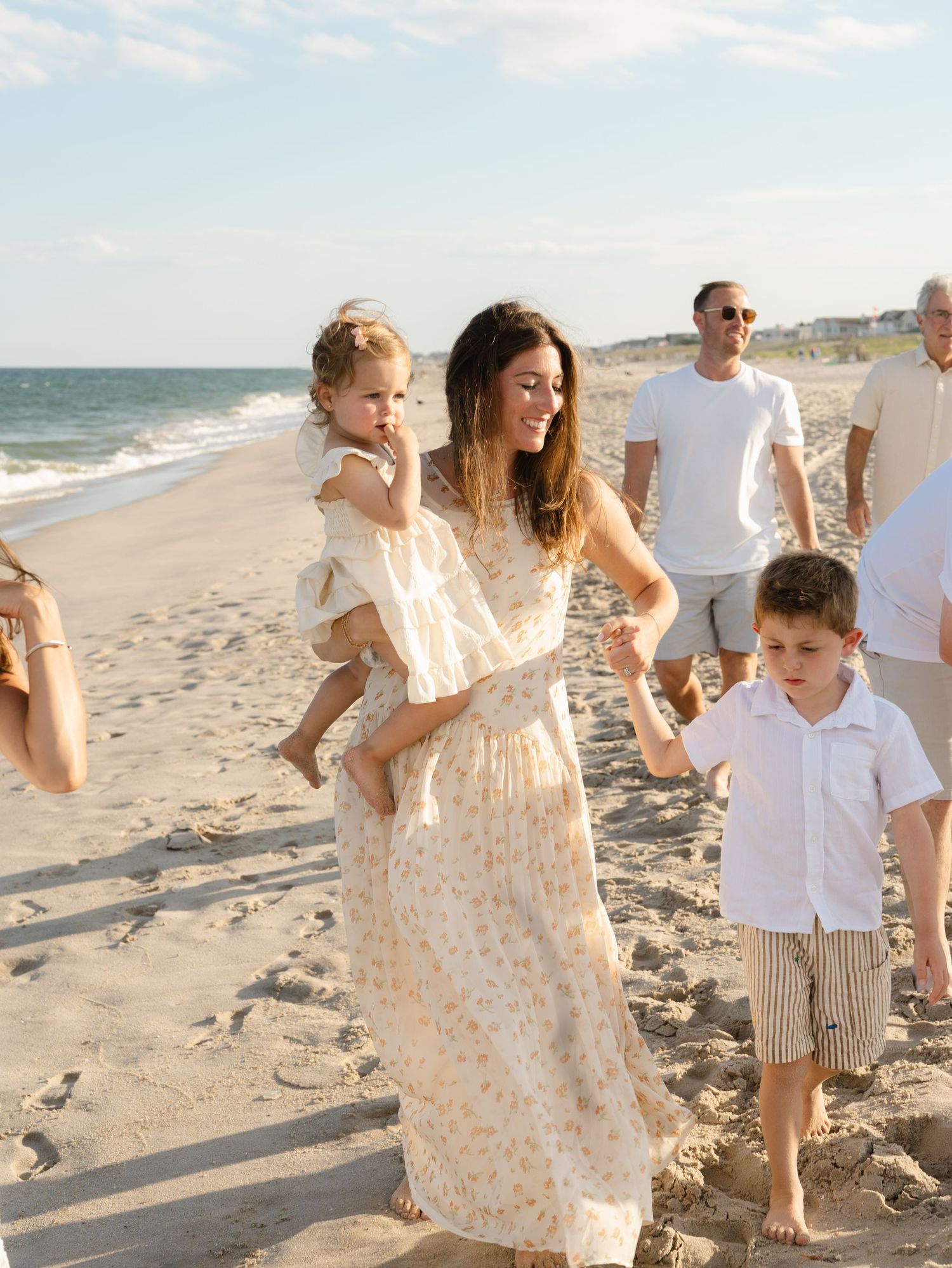 Extended family walks down the beach playing and laughing together.