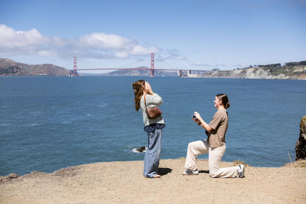 Woman proposing to her partner at Lands End with Golden Gate Bridge