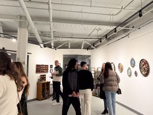 Visitors browse artwork at a modern gallery opening with white walls and decorative ceramic pieces on display.