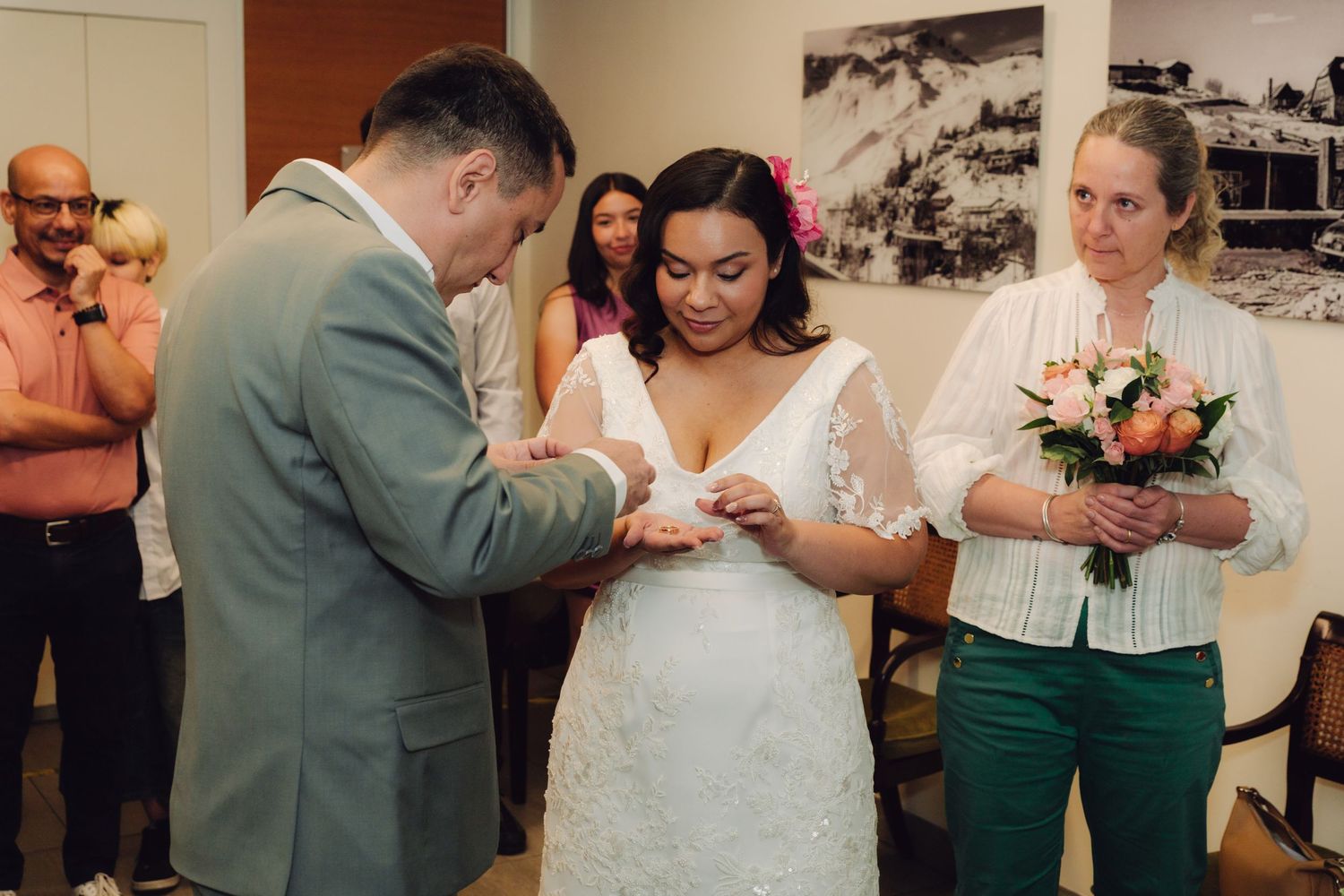 Groom places wedding ring on brides finger during intimate civil ceremony indoors.