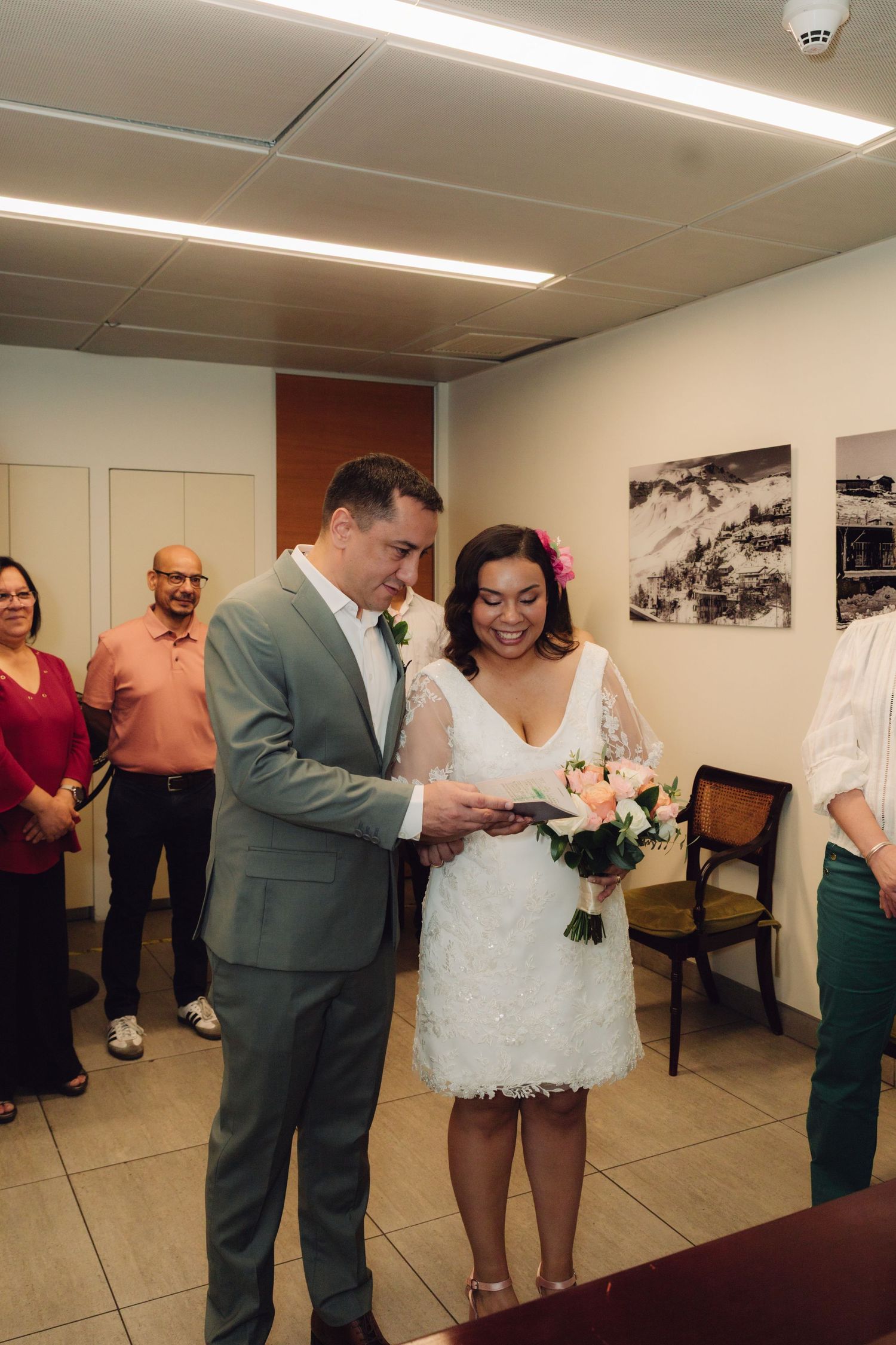 Bride and groom read vows together during intimate civil wedding ceremony with guests watching.