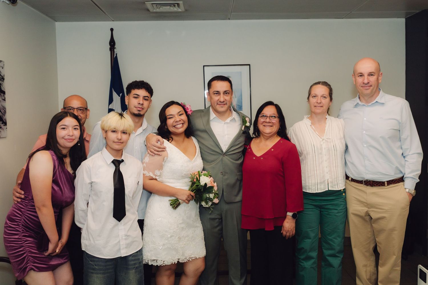 Newlyweds surrounded by smiling family members for group photo at intimate courthouse wedding celebration.