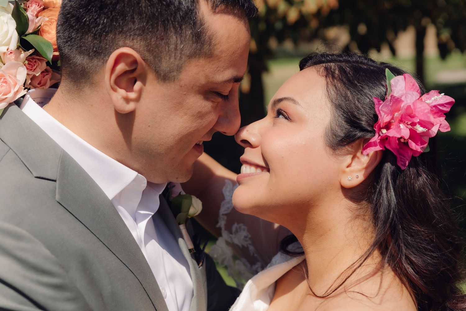 Bride and groom share an intimate forehead-to-forehead moment outdoors on their sunny wedding day.